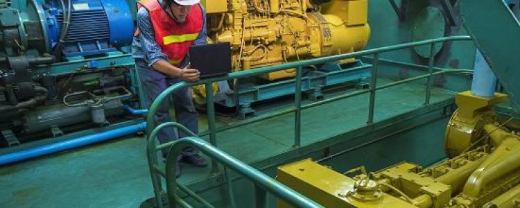 Asian young engineer in reflective clothing with helmet using laptop computer to checking engine quality system inside of engine room of fishing vessel